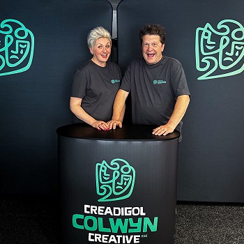 Libby & Stuart Loughland o flaen cefndir gyda logo Creadigol Colwyn Creative