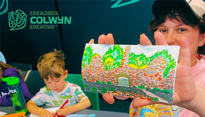 A child showing a picture she has drawn and coloured using a variety of colours