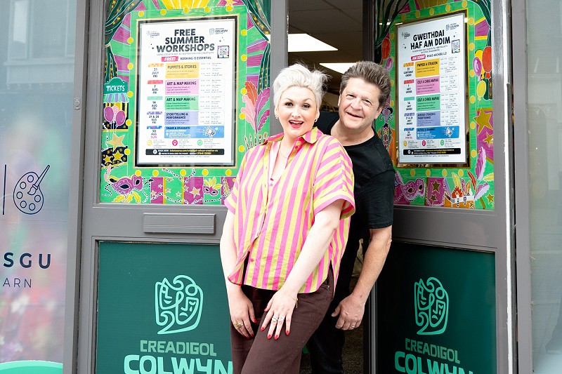 Libby & Stuart Loughland yn gwenu wrth ddrws ffrynt Creadigol Colwyn Creative